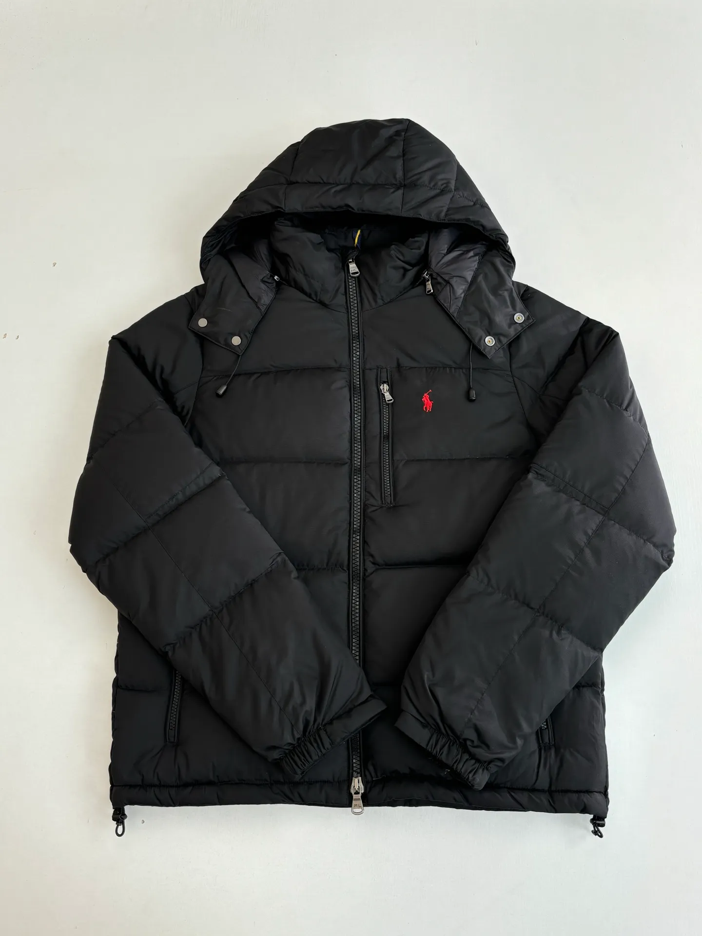 P970 Rah Laure*/Ralph Lauren solid color classic red label pony embroidered hooded down jacket. The nylon fabric has good windproof and waterproof properties, which can effectively block the intrusion of wind and rain from the outside and keep the interior dry. It is suitable for wearing in humid or rainy environments. The chest label uses an imported MEO embroidery machine. It first scans the original pattern and then uses high-quality silk thread to make a pattern. The density effect is adjusted by continuous pattern making. Detachable: Equipped with detachable nylon, users can easily disassemble or install it according to weather changes or personal preferences, which is both practical and convenient. Exquisite details: the zipper design is simple and elegant, easy to operate; the closing design of the cuffs and hem effectively prevents the intrusion of cold wind, improving the warmth and comfort of wearing. It uses 90 white duck down with a weight of 260g to ensure excellent thermal insulation performance. After strict screening and processing, the velvet is not easy to get drilled, ensuring durability. The overall wiring is straight and delicate, the fabric is comfortable and soft, and the color is consistent without color difference. It can be matched with the same style to create a fashionable look and control various occasions. Customized accessories, complete with three standards, same style for men and women!  Size: S/M/L/XL/XXL